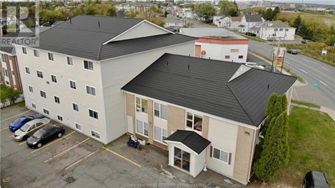 A large white building with a black roof and a parking lot in front.