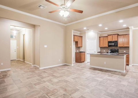 A spacious living room with a kitchen area in the background.