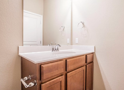 A bathroom with a white sink and brown drawers.