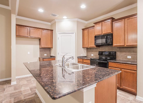 A kitchen with a granite countertop and wooden cabinets.