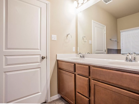 A bathroom with a white door, brown drawers, and a white sink.