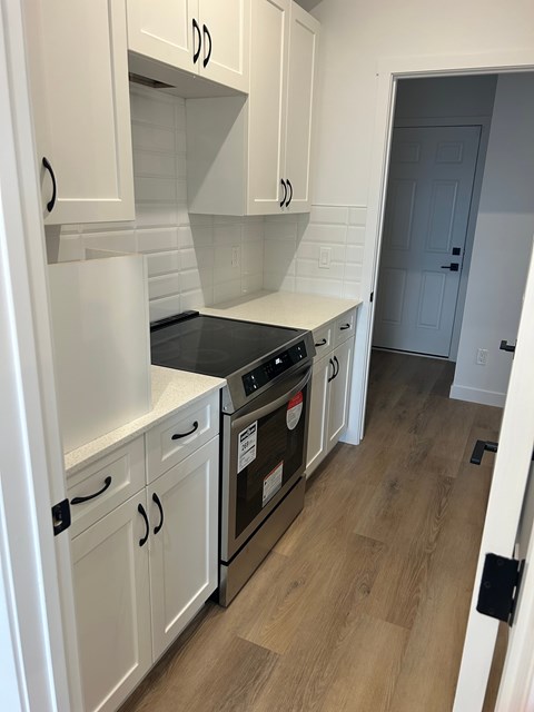 A kitchen with white cabinets and a black stove top oven.