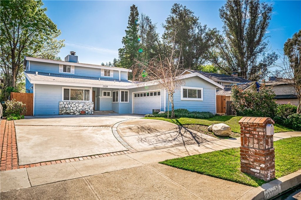 A blue house with a white garage door and a brick mailbox.