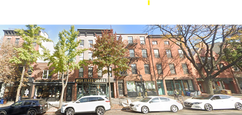 A street view with cars parked in front of a building with a sign that says "MIDDLE GIRLS".