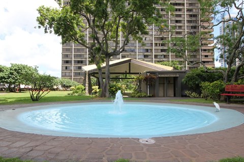 A fountain in the middle of a pool surrounded by a brick border.