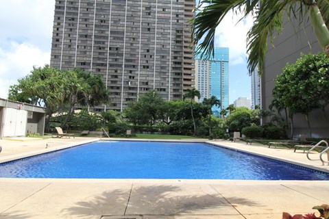 A large swimming pool in the middle of a city with a tall building in the background.