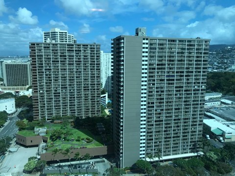 Two large buildings are seen from above with a green area in between.