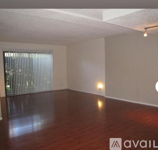 A room with wooden floors and a window with blinds.