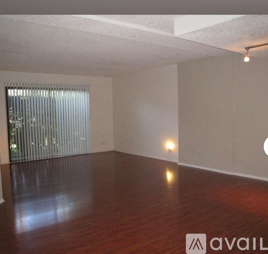 A room with wooden floors and a window with blinds.