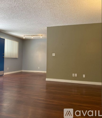 A room with wooden flooring and a wall with a switch.