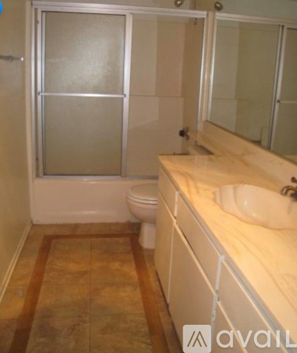 A bathroom with a toilet, sink and mirror.