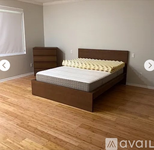 A bed with a wooden headboard and footboard sits in a room with wooden flooring.