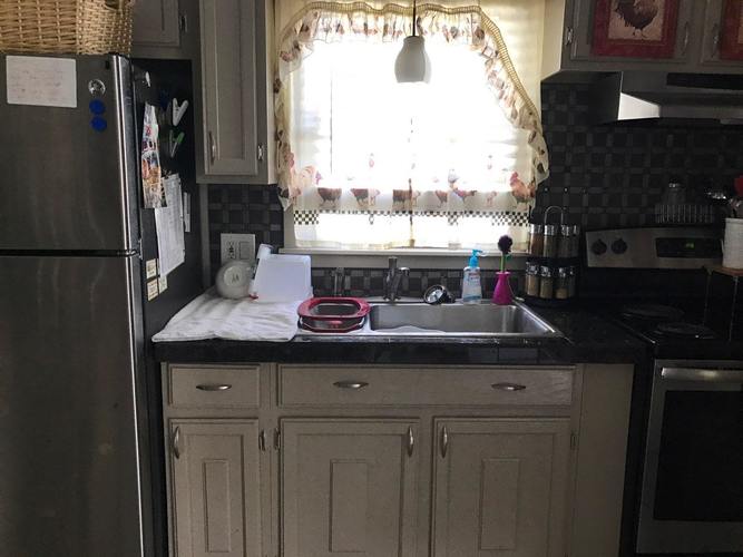 A kitchen with a refrigerator, sink, and cabinets.
