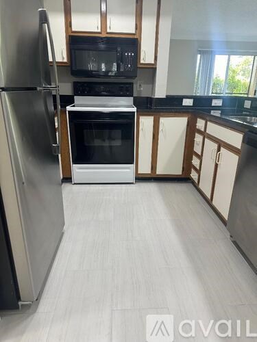 A kitchen with a refrigerator, oven, and microwave.