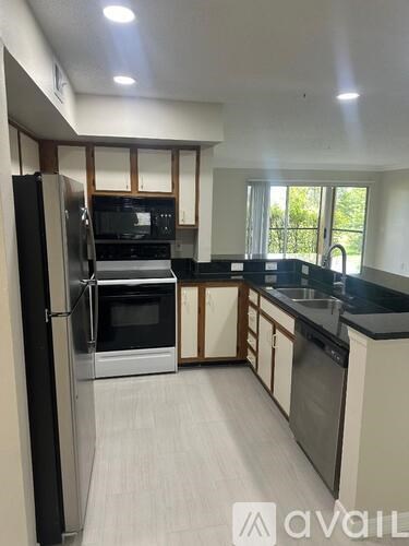 A kitchen with black countertops and stainless steel appliances.