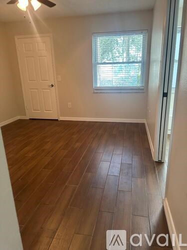 A room with wooden flooring and a window with blinds.
