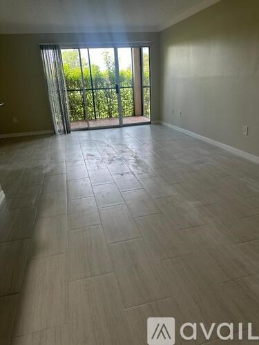 A room with a tiled floor and sliding glass doors leading to a green outdoor area.