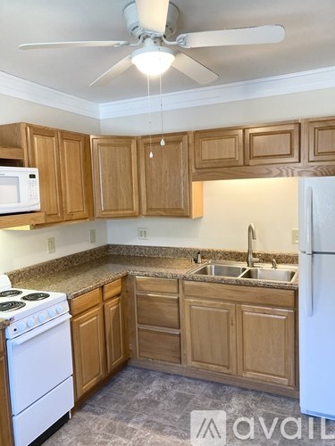 A kitchen with a white refrigerator and wooden cabinets.