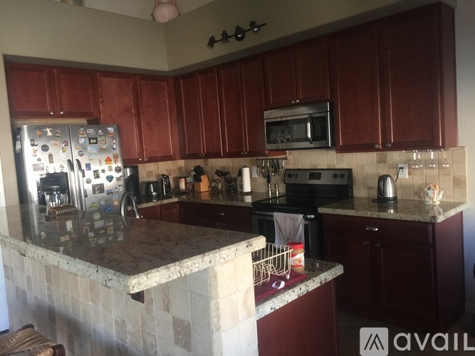 A kitchen with a refrigerator, microwave, oven, and sink.
