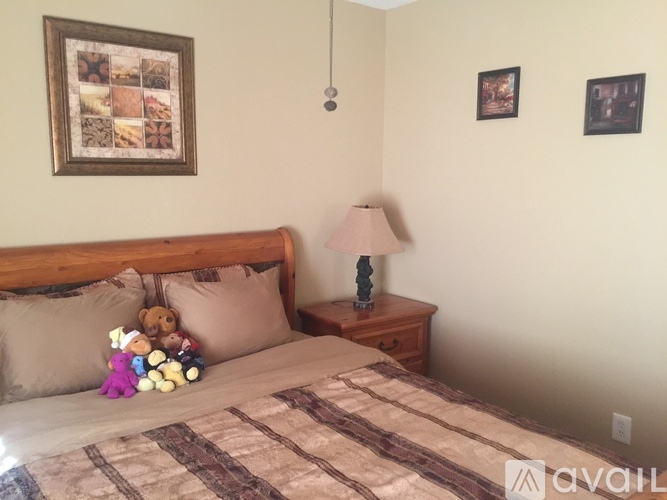 A bedroom with a bed, a nightstand with a lamp, and pictures on the wall.