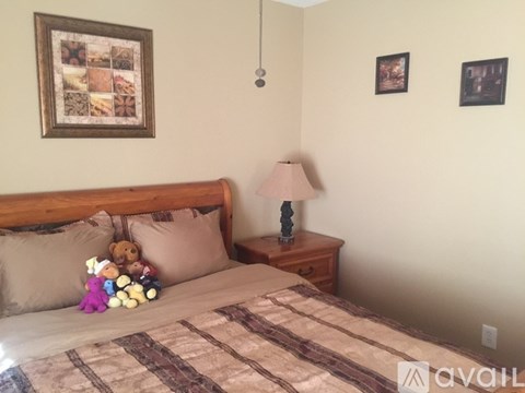 A bedroom with a bed, a nightstand with a lamp, and pictures on the wall.