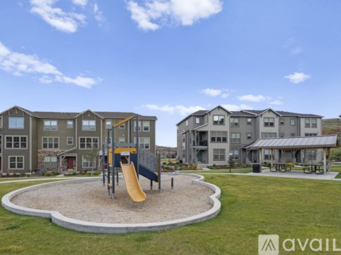 A playground with a yellow slide in front of apartment buildings.