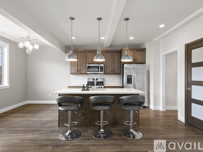 A modern kitchen with a bar area and a refrigerator in the background.