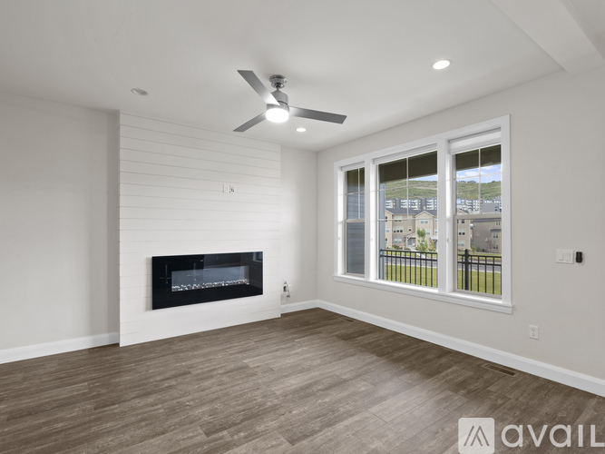A spacious living room with a fireplace and a ceiling fan.
