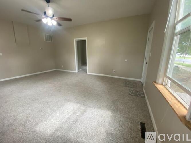 A spacious room with a ceiling fan and carpeted floor.