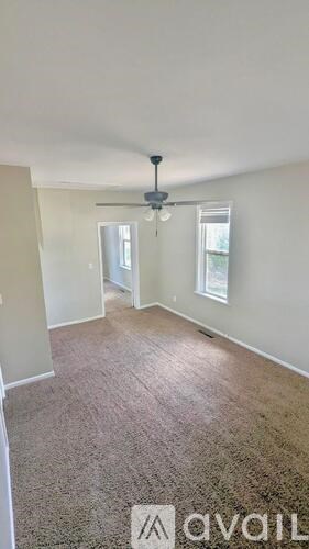A room with a ceiling fan and two windows.
