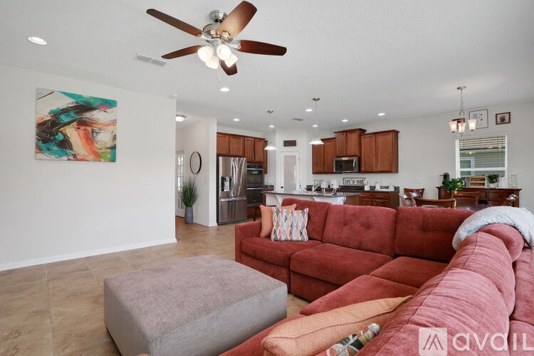 A living room with a red couch and a ceiling fan.