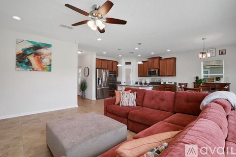 A living room with a red couch and a ceiling fan.