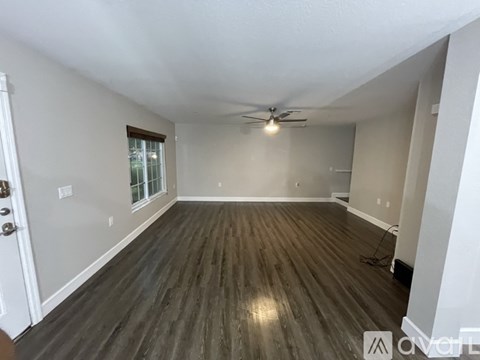 A spacious room with a ceiling fan and wooden flooring.