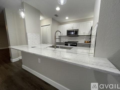 A kitchen with white cabinets and a marble countertop.