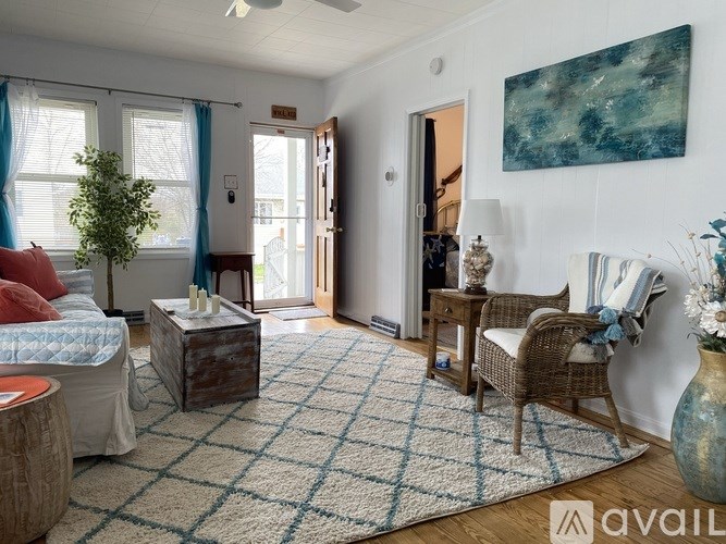 A living room with a wicker chair and a blue rug.