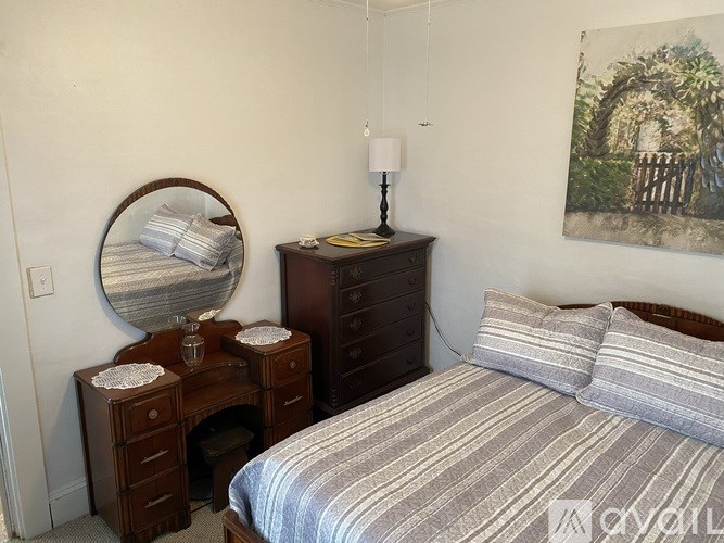 A bedroom with a bed, nightstand, and a painting on the wall.
