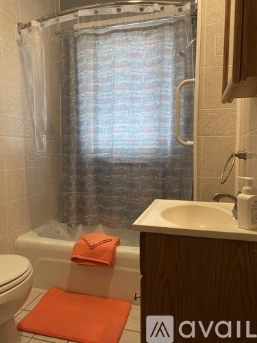 A bathroom with a toilet, a shower with a curtain, a sink and a towel.