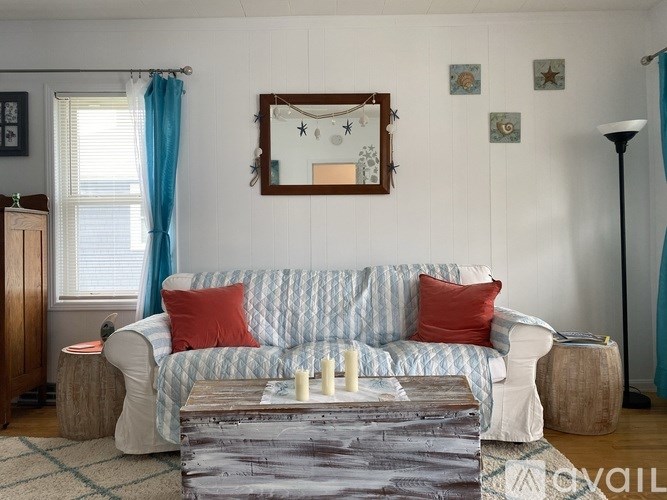 A living room with a white couch and a mirror above it.