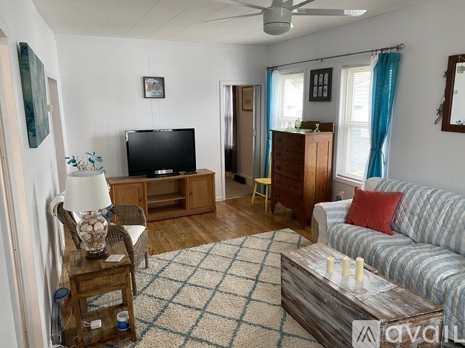 A living room with a television, a couch, and a rug.