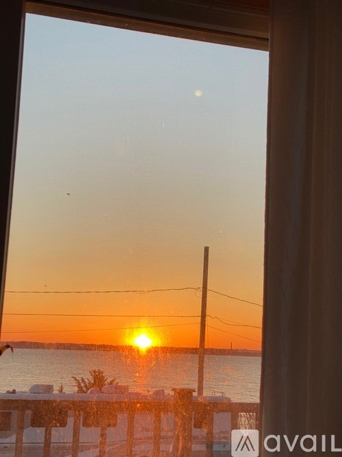 A sunset view from a window with a wooden fence in the foreground.