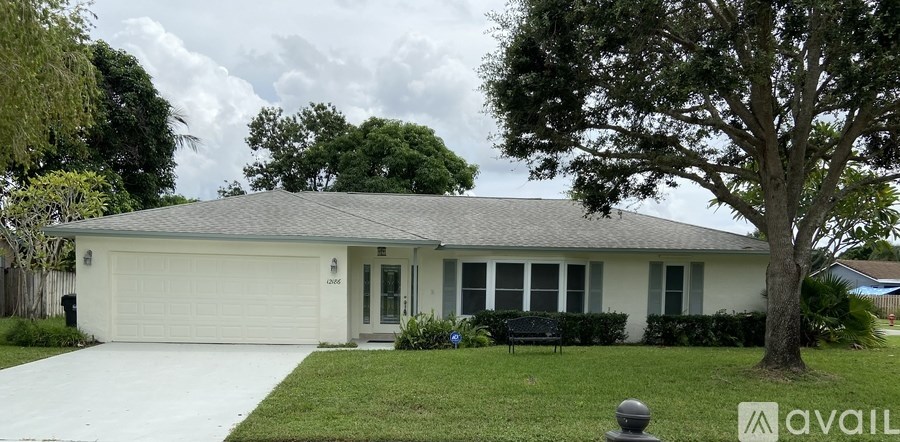 A house with a white garage door and a tree in front.
