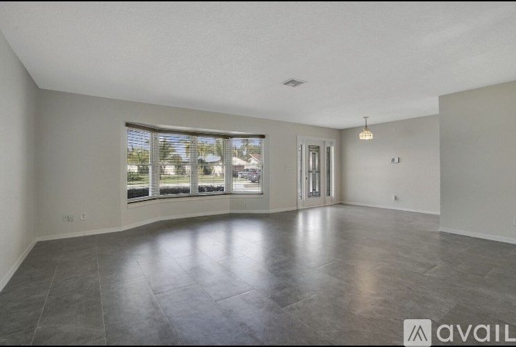 A spacious room with a large window and a door leading to another room.