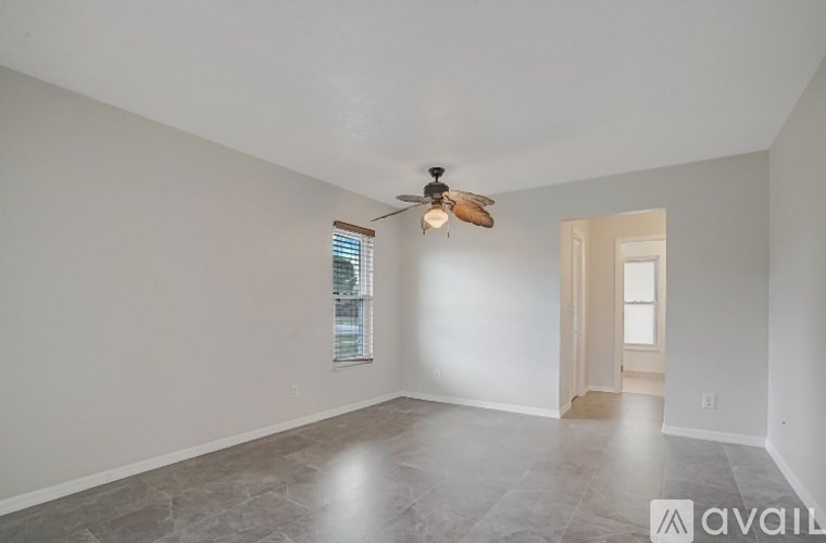 A spacious room with a ceiling fan and a door leading to another room.