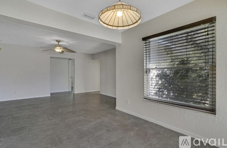 A room with a ceiling fan and a window with blinds.