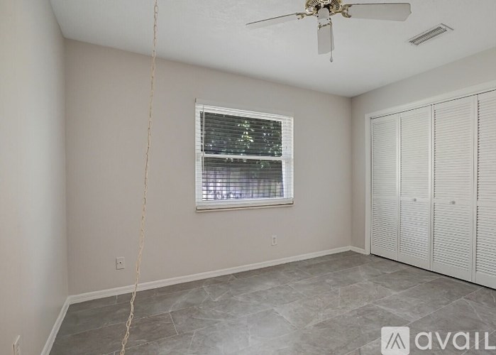 A room with a ceiling fan, a window with blinds, and a wall with a switch.