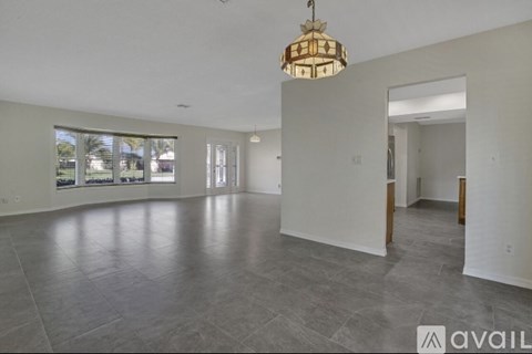 A spacious room with a large chandelier and tiled flooring.