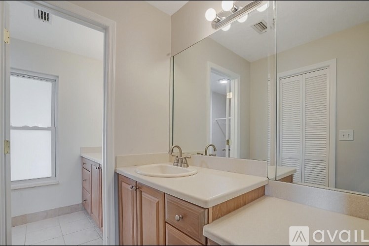 A bathroom with a sink, mirror, and a window.