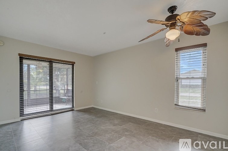 A room with a ceiling fan and a window with blinds.