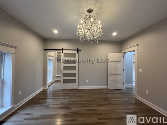 A spacious room with a chandelier and a staircase leading to the second floor.