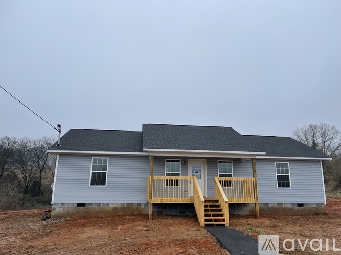 A house with a grey roof and a wooden deck is available for sale.